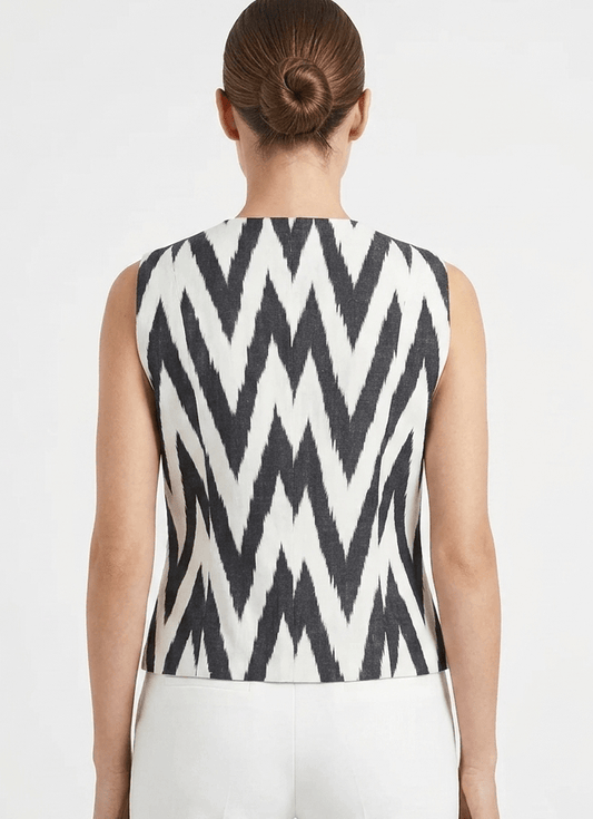 Person wearing a sleeveless top with a silk ikat vest black and white zigzag pattern on a plain background