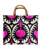 Borsa tote in velluto ikat fucsia e nero con motivo a melograno e manici in bambù. Fatto a mano ed elegante, ideale per l’uso quotidiano o occasioni speciali. Design unico e tessuto di alta qualità.