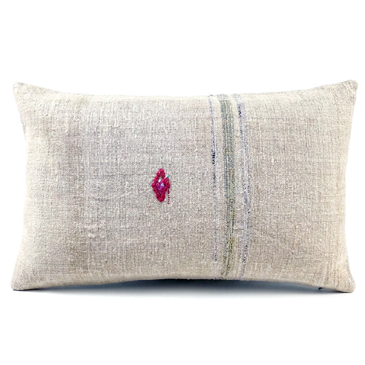 A rectangular lumbar throw pillow made of textured beige linen fabric, featuring a vertical stripe pattern in muted blue and green tones and a small magenta embroidered diamond on the front, set against a plain white background.
