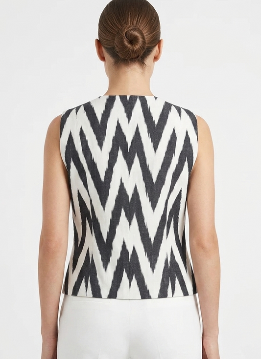 Person wearing a sleeveless top with a silk ikat vest black and white zigzag pattern on a plain background