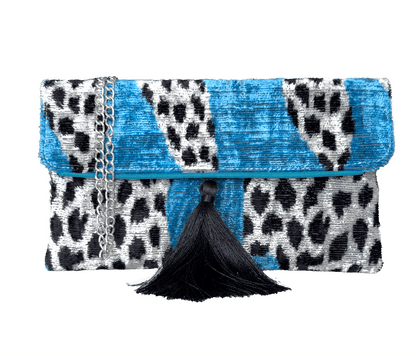 Blue silk velvet ikat clutch bag with black and white pattern and tassel on a white background