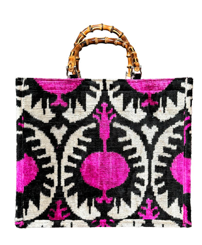 Borsa tote in velluto ikat fucsia e nero con motivo a melograno e manici in bambù. Fatto a mano ed elegante, ideale per l’uso quotidiano o occasioni speciali. Design unico e tessuto di alta qualità.