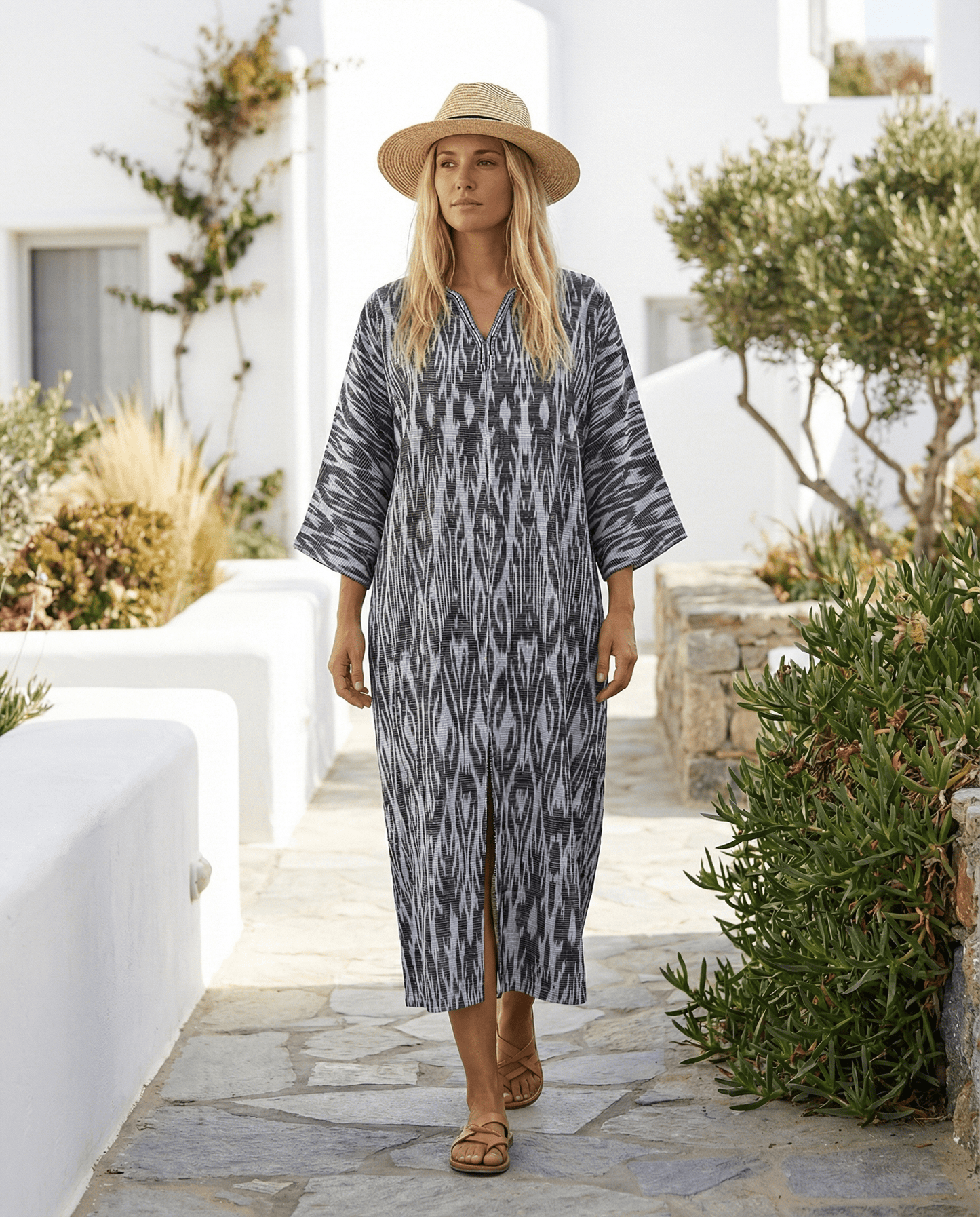 Woman wearing a cotton ikat dark grey and white patterned dress and hat in a garden setting