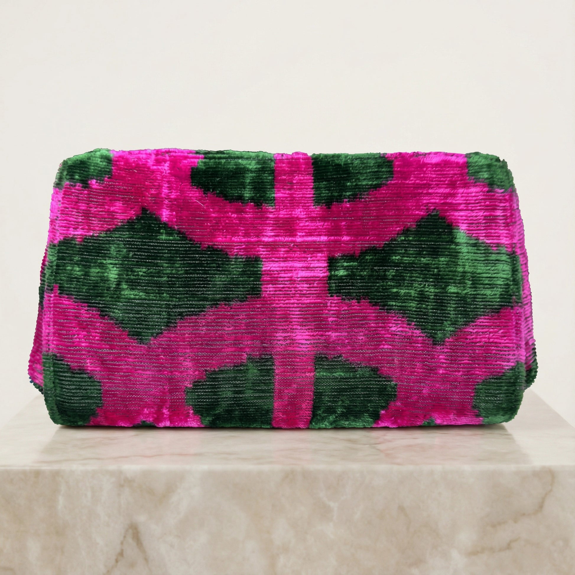Pink and green patterned clutch bag on a light background