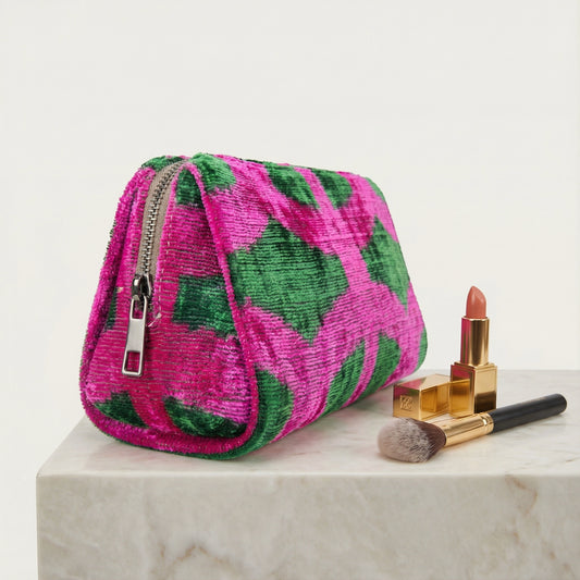Pink and green patterned makeup bag with cosmetics on a light background