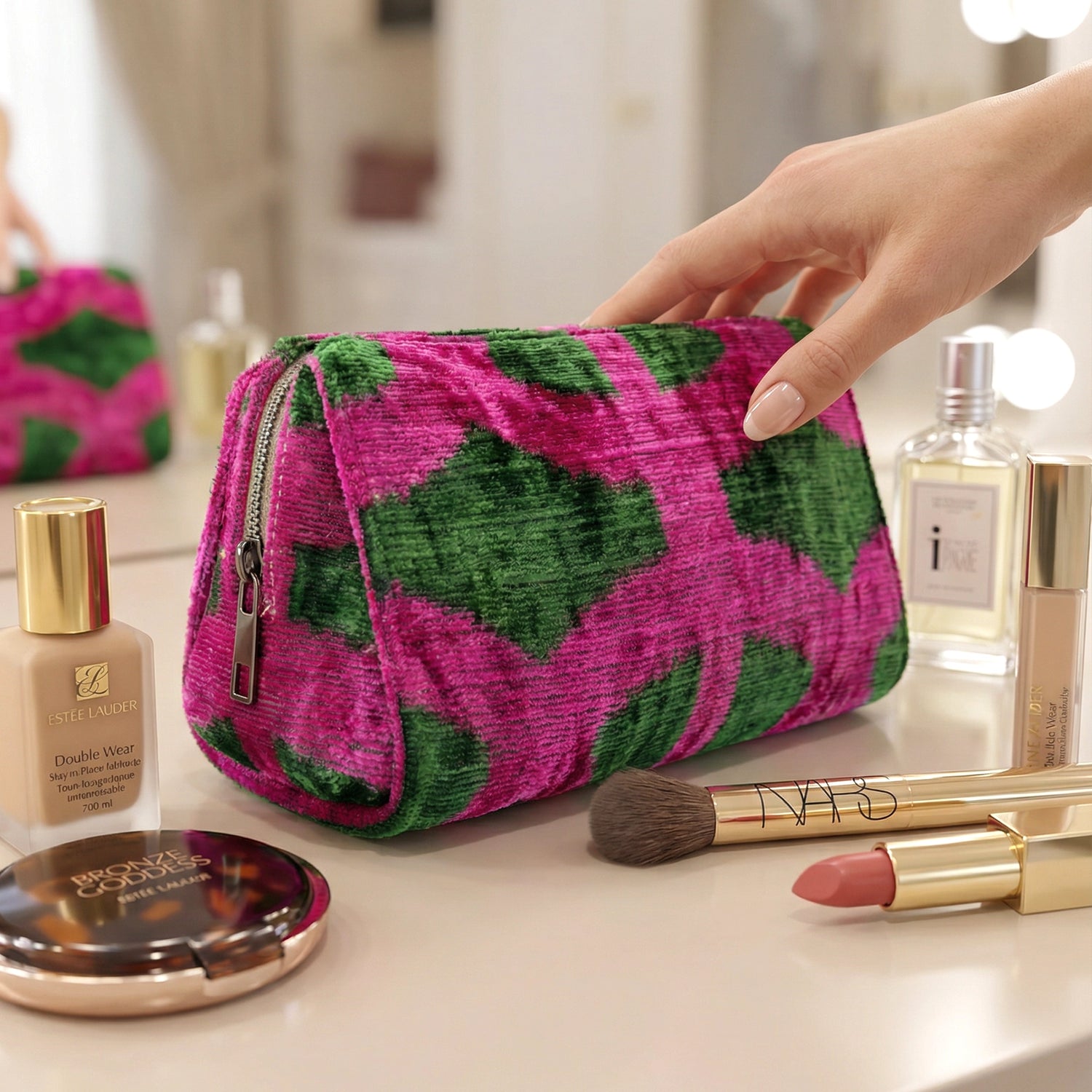 Pink and green patterned makeup bag on a vanity with cosmetic items.