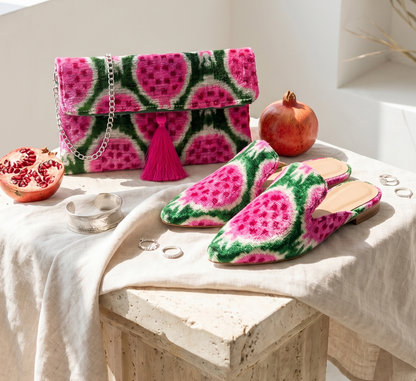Watermelon-patterned slippers and handbag on a table with pomegranates.