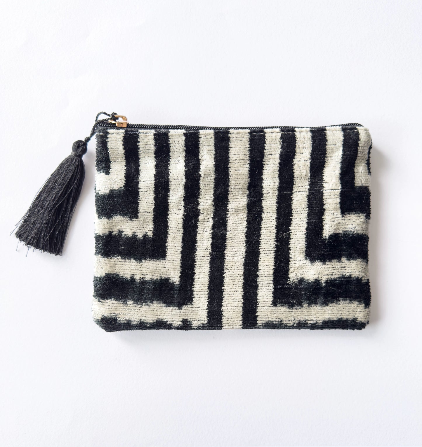 Black and white patterned pouch with a tassel on a light gray background
