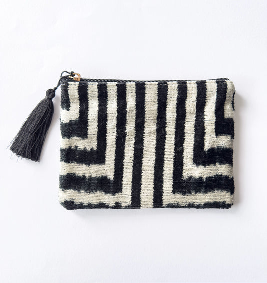 Black and white patterned pouch with a tassel on a light gray background