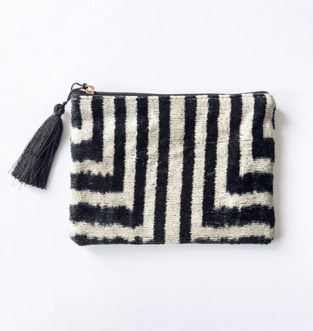 Black and white patterned pouch with a tassel on a light gray background
