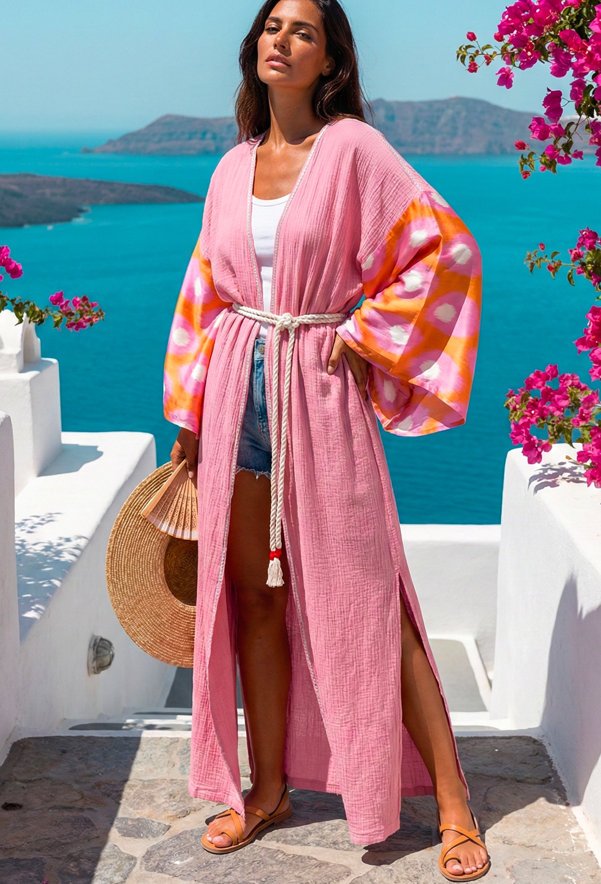Woman in a The Blush Artisan Silk Ikat & Muslin kimono standing in a scenic location with blue water and white buildings.