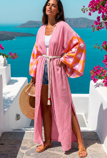 Woman in a The Blush Artisan Silk Ikat & Muslin kimono standing in a scenic location with blue water and white buildings.