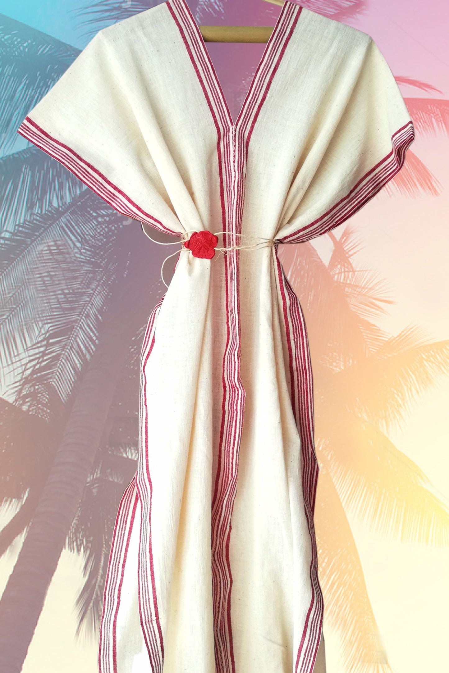 Traditional garment with red accents on a hanger against a blurred natural background