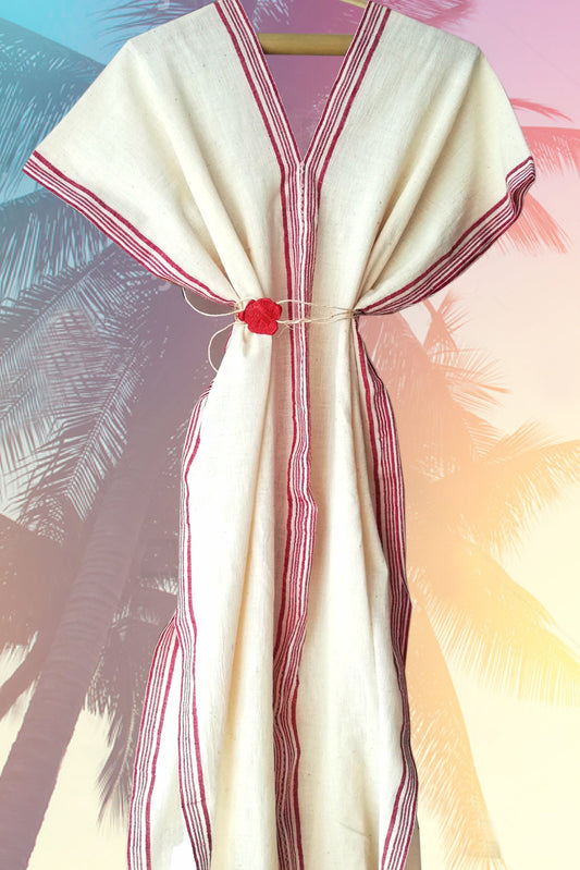 Traditional garment with red accents on a hanger against a blurred natural background